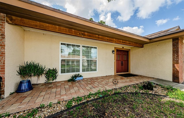 view of exterior entry with a patio area