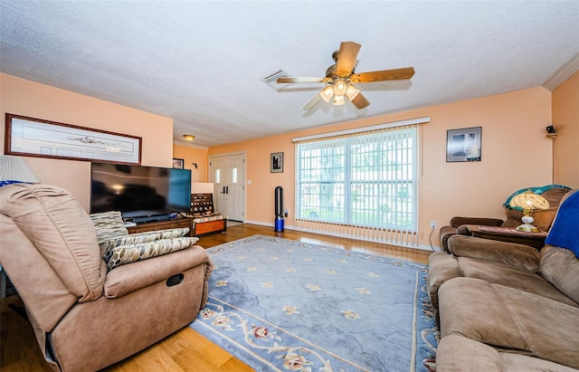 living room featuring ceiling fan, hardwood / wood-style flooring, and a textured ceiling