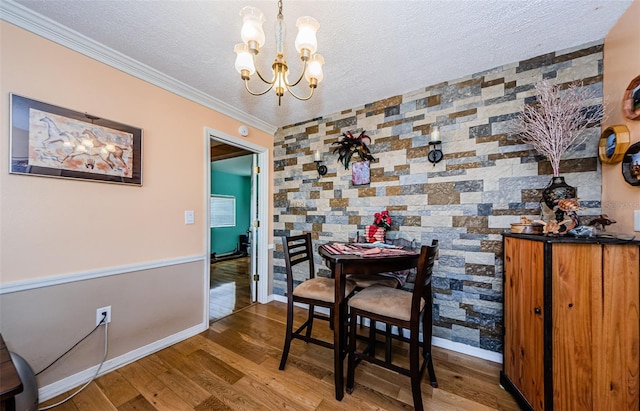 dining room featuring wood-type flooring, an inviting chandelier, ornamental molding, and a textured ceiling