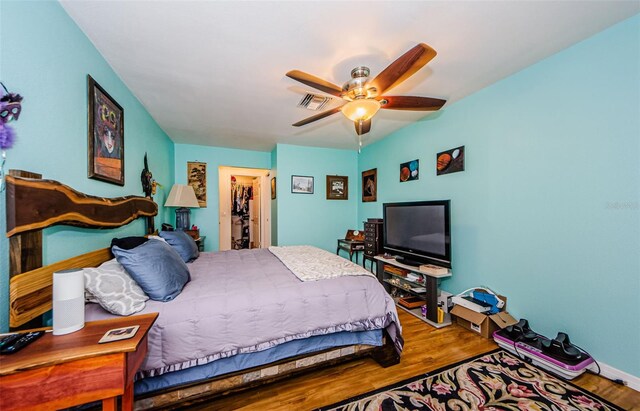 bedroom featuring wood-type flooring, ceiling fan, and a walk in closet