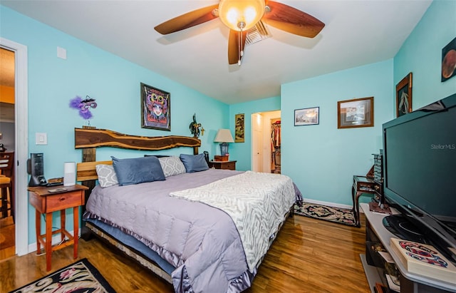 bedroom featuring ceiling fan, a closet, dark hardwood / wood-style floors, and a walk in closet