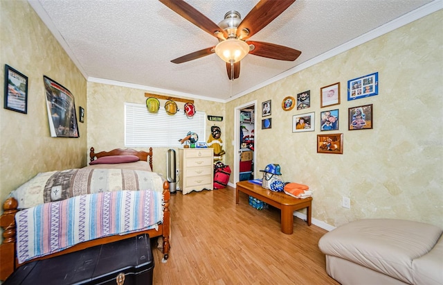 bedroom with light wood-type flooring, a textured ceiling, ornamental molding, and ceiling fan