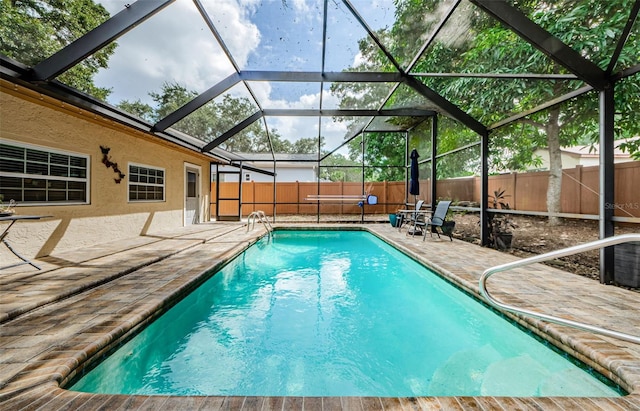 view of swimming pool featuring a patio and glass enclosure