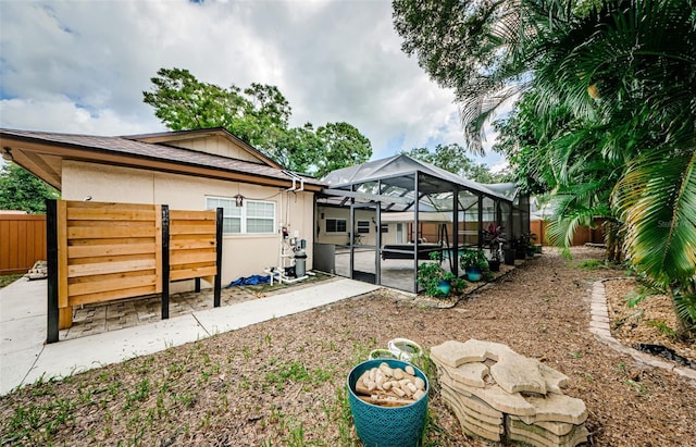 back of house featuring glass enclosure and a patio