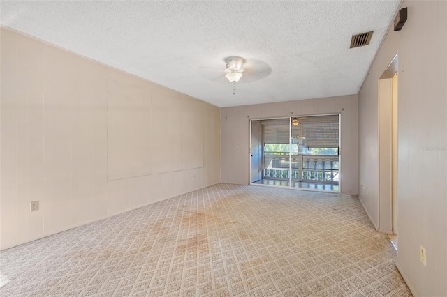 carpeted spare room featuring a textured ceiling and ceiling fan