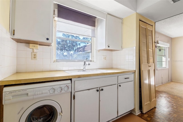 kitchen featuring washer / dryer, sink, decorative backsplash, and white cabinets