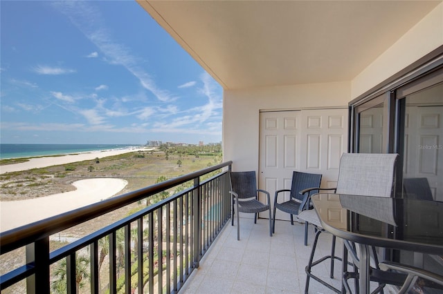 balcony with a water view and a view of the beach