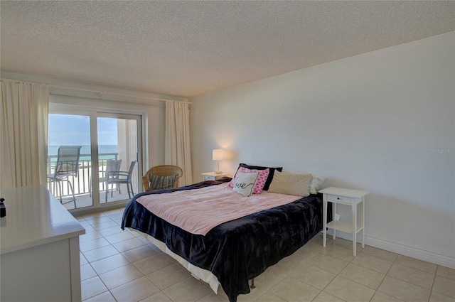 bedroom featuring a textured ceiling, access to outside, light tile patterned floors, and a water view