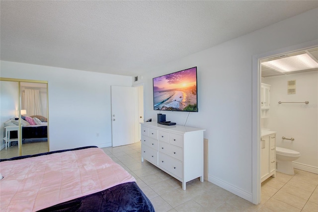 tiled bedroom featuring ensuite bathroom and a textured ceiling