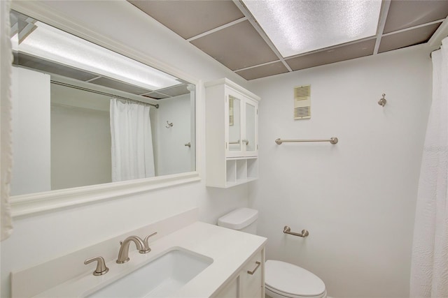 bathroom with vanity, toilet, walk in shower, and a drop ceiling