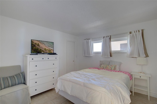 bedroom featuring light tile patterned floors and a textured ceiling