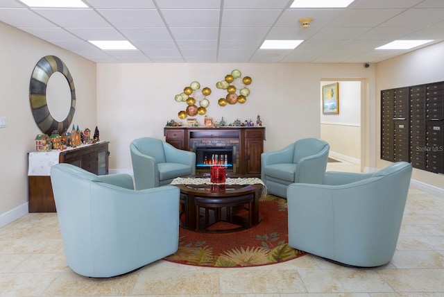 living room with a paneled ceiling, mail boxes, and light tile patterned flooring