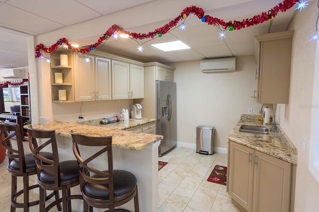 kitchen featuring light stone countertops, a wall unit AC, stainless steel refrigerator with ice dispenser, and a breakfast bar