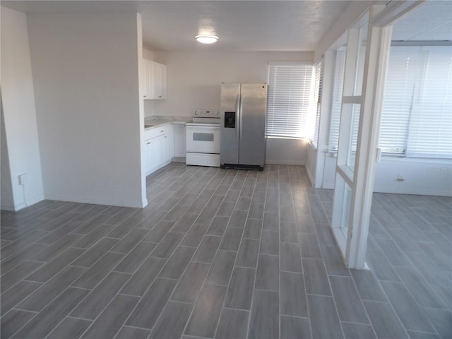 kitchen with white electric range, dark wood-type flooring, white cabinetry, and stainless steel refrigerator with ice dispenser