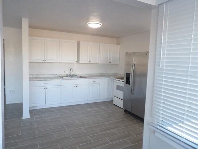 kitchen with sink, stainless steel fridge, white range with electric cooktop, and white cabinets