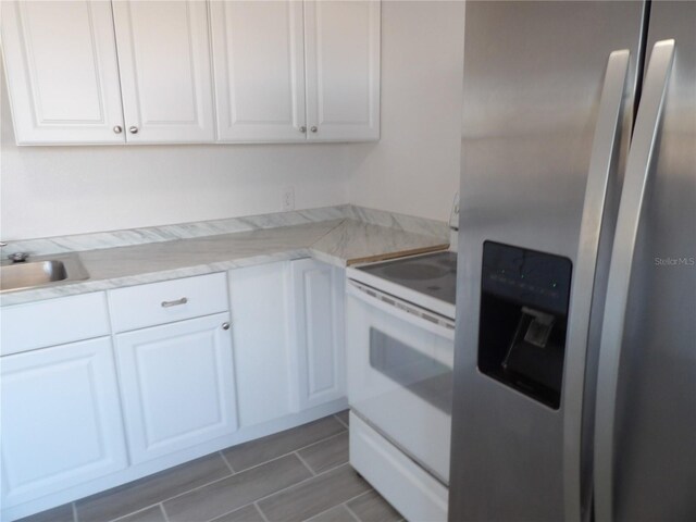 kitchen featuring white cabinets, light stone countertops, white range with electric cooktop, sink, and stainless steel refrigerator with ice dispenser