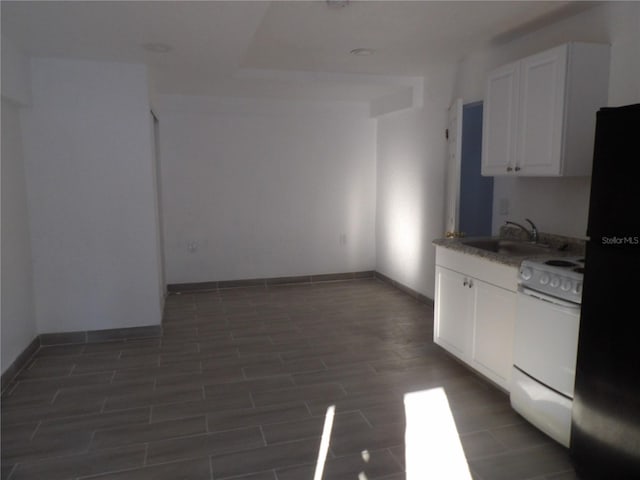 kitchen featuring dark wood-type flooring, white cabinetry, sink, white range, and black fridge