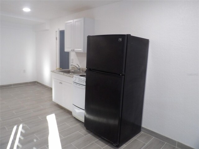 kitchen featuring white cabinetry, light hardwood / wood-style flooring, white range oven, sink, and black fridge