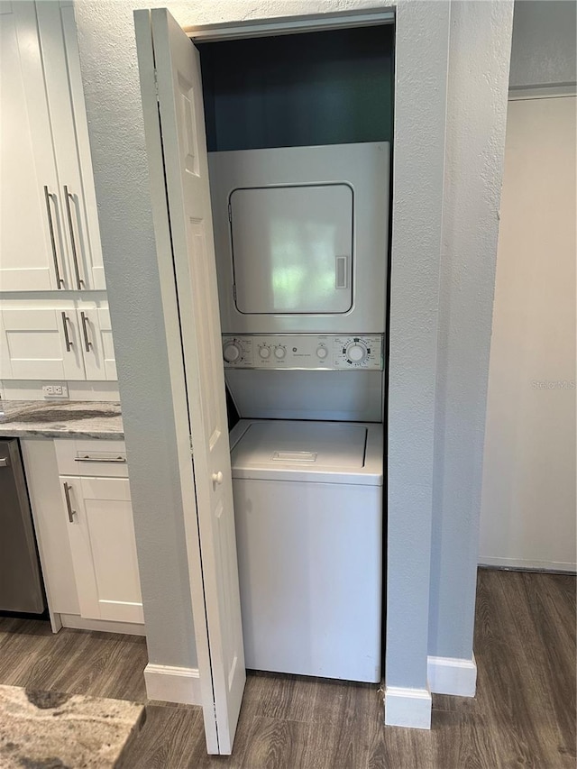 laundry room featuring dark hardwood / wood-style floors and stacked washer / dryer