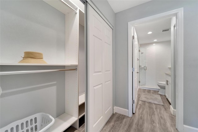 interior space with toilet, hardwood / wood-style flooring, and walk in shower