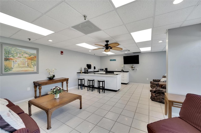 living room with a paneled ceiling, ceiling fan, and light tile patterned floors