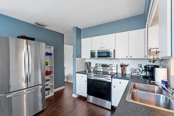 kitchen with white cabinets, appliances with stainless steel finishes, sink, dark wood-type flooring, and tasteful backsplash