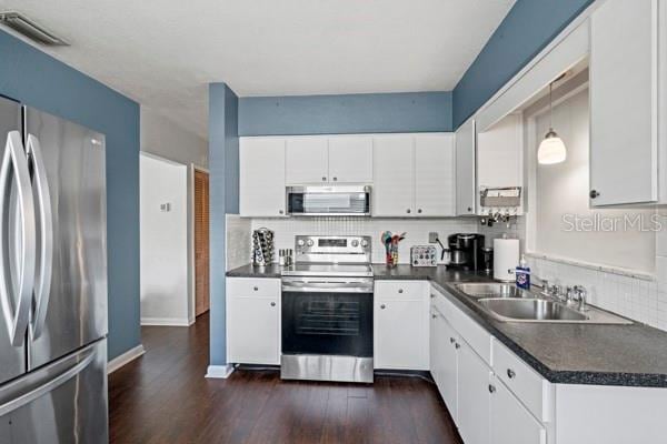 kitchen with sink, dark hardwood / wood-style floors, appliances with stainless steel finishes, and white cabinetry