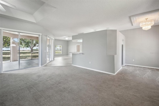 unfurnished living room with ceiling fan with notable chandelier, a textured ceiling, and carpet