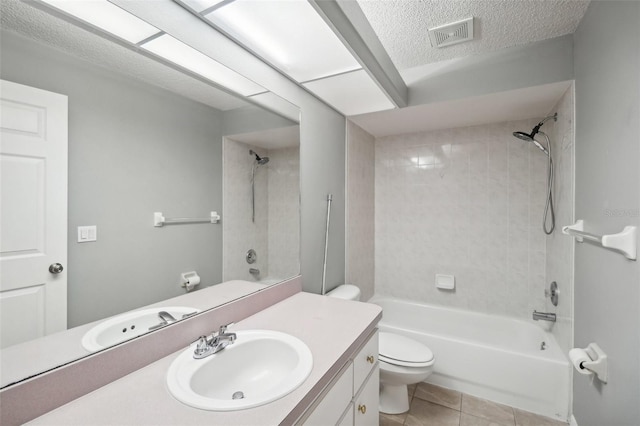 full bathroom featuring tiled shower / bath combo, toilet, vanity, tile patterned floors, and a textured ceiling