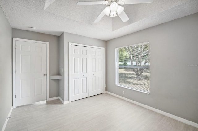 unfurnished bedroom featuring light wood-type flooring, a textured ceiling, ceiling fan, and a closet