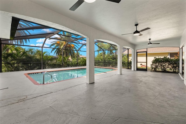 view of pool featuring glass enclosure, a patio area, and ceiling fan