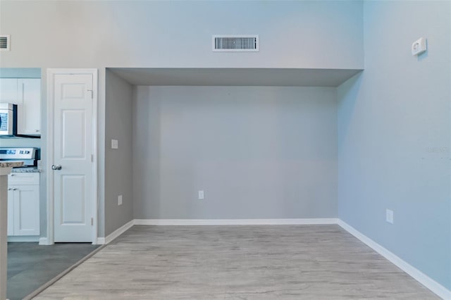 unfurnished room featuring light wood-style floors, visible vents, and baseboards