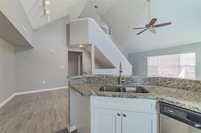 kitchen with light stone counters, light wood finished floors, stainless steel dishwasher, white cabinetry, and a sink