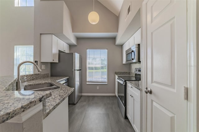 kitchen featuring white cabinets, light stone counters, stainless steel appliances, and sink