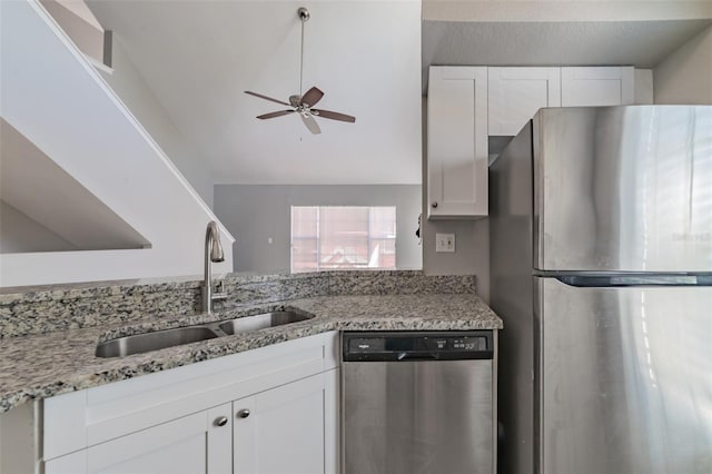 kitchen featuring appliances with stainless steel finishes, white cabinets, a sink, and light stone counters