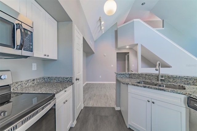 kitchen with appliances with stainless steel finishes, lofted ceiling, white cabinetry, and a sink