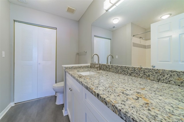 bathroom with toilet, wood finished floors, vanity, and visible vents