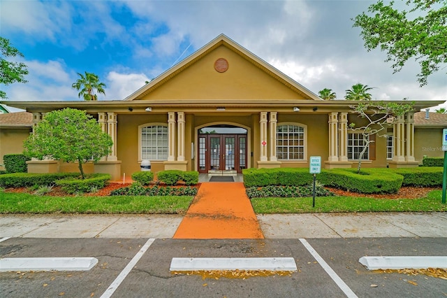 view of front of home with uncovered parking, french doors, and stucco siding