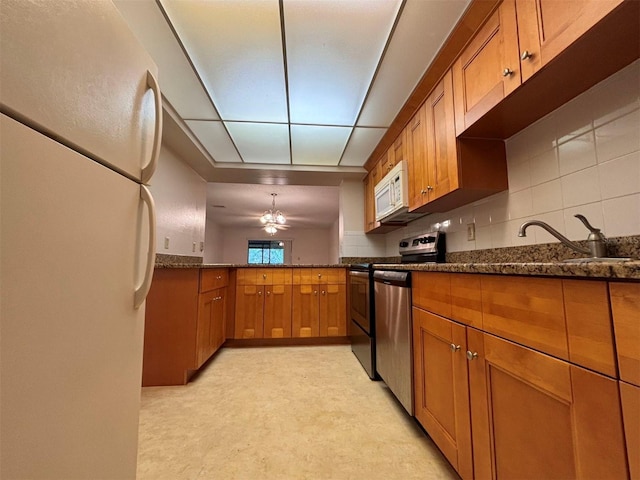 kitchen with dark stone countertops, backsplash, stainless steel appliances, and ceiling fan