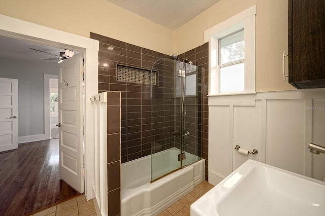 bathroom featuring ceiling fan, hardwood / wood-style flooring, and bath / shower combo with glass door