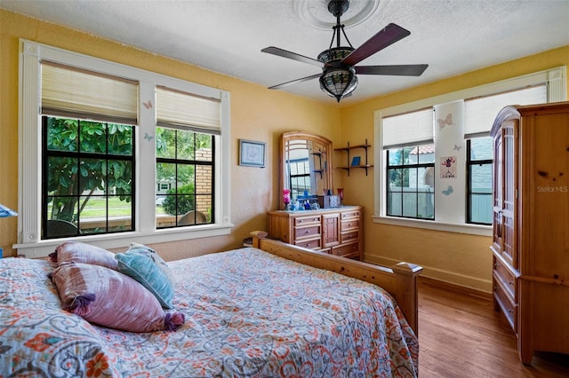 bedroom featuring ceiling fan, hardwood / wood-style flooring, and a textured ceiling