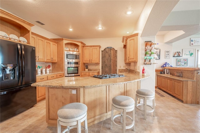 10177 Sunburst Ct, Spring Hill, FL 34608 - kitchen with light brown cabinetry, a peninsula, appliances with stainless steel finishes, and visible vents