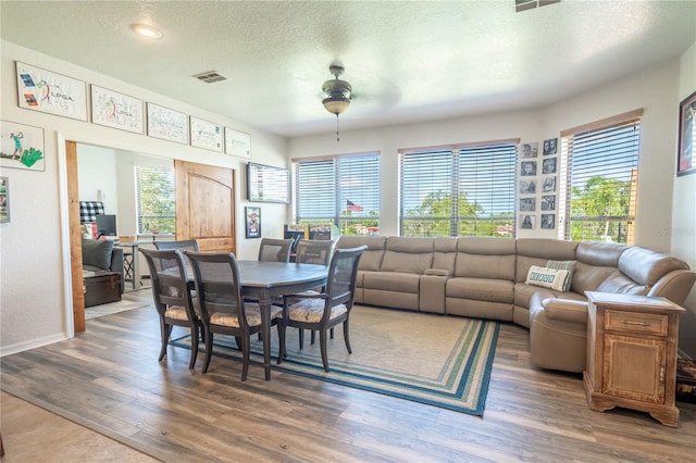 dining space with dark wood-type flooring, ceiling fan, and a textured ceiling