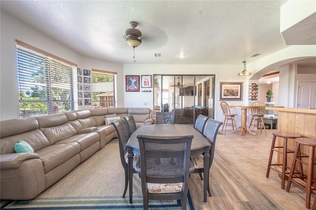 living room featuring a textured ceiling, ceiling fan, and light hardwood / wood-style floors