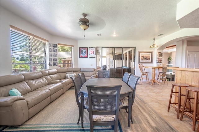 10177 Sunburst Ct, Spring Hill, FL 34608 - dining area featuring arched walkways, a textured ceiling, a ceiling fan, and light wood finished floors