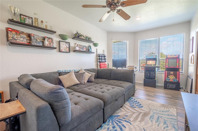 living room featuring light wood-type flooring, ceiling fan, and a textured ceiling