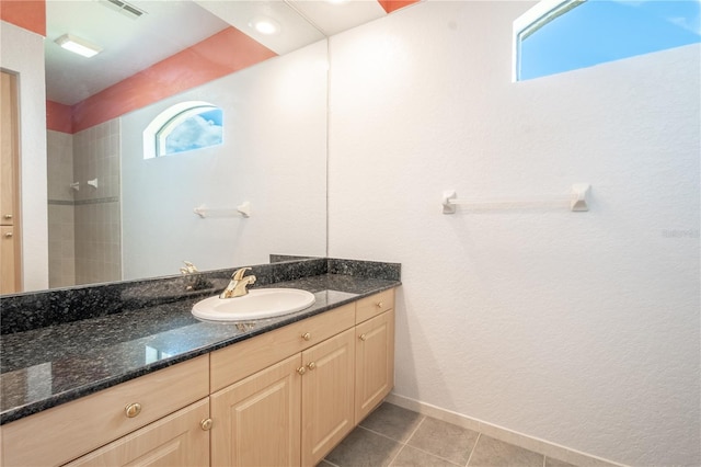 bathroom featuring tile patterned floors, a tile shower, and vanity