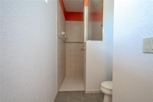 bathroom with tiled shower, toilet, and tile patterned floors