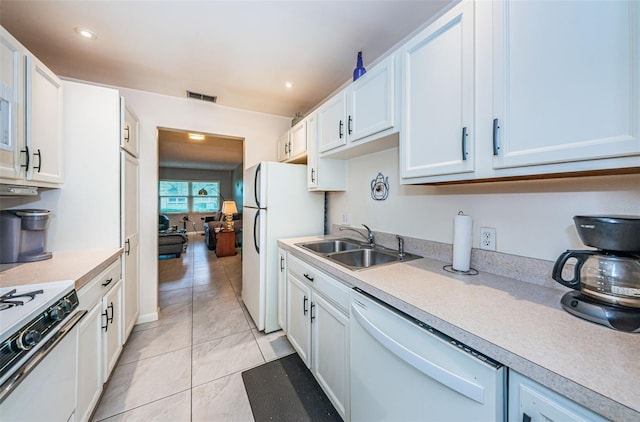 kitchen with light tile patterned flooring, white appliances, white cabinetry, and sink