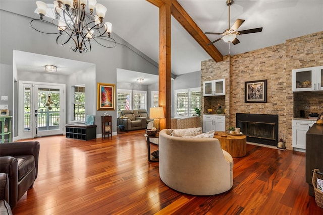 living room featuring a wealth of natural light, ceiling fan with notable chandelier, high vaulted ceiling, and a fireplace